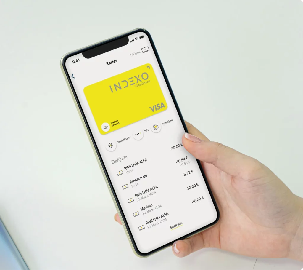Рука держит смартфон, на котором отображается банковское приложение с желтой картой Visa и последними транзакциями.